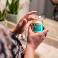 Nursing Salve Jar with person applying to fingers